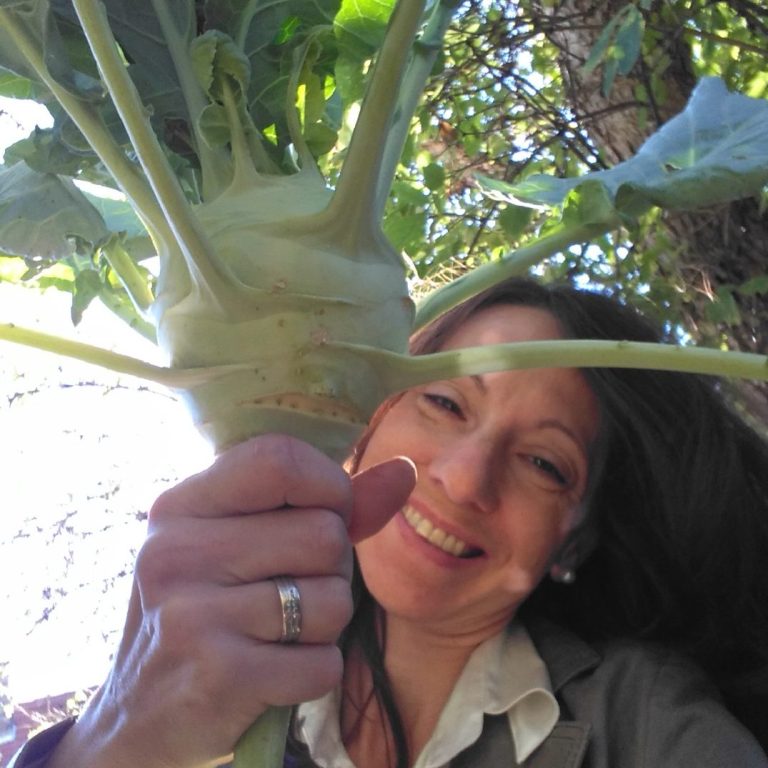 Annemarie hält einen großen Kohlrabi und lächelt dabei.